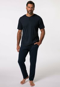 Námořnický modrý set domácího oblečení, který zahrnuje triko s krátkým rukávem a vzorovaným designem s henley výstřihem a odpovídající dlouhé kalhoty se bočními kapsami.