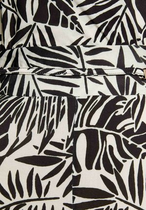 Tissu à motif de feuilles tropicales en noir et blanc, avec ceinture étroite assortie et détail de boucle dorée.