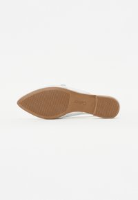 Chaussure plate argentée à bout rond, présentant une semelle en caoutchouc brun texturé et des accents transparents sur la partie supérieure.