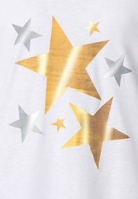 Biała bawełniana koszulka z wzorami metalicznych gwiazd w kolorze złotym i srebrnym o różnych rozmiarach. Gwiazdy są błyszczące i mają gładką teksturę.