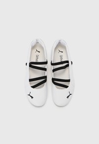 Ballerines blanches avec des sangles élastiques noires, dessus synthétique lisse, bout arrondi et logo Puma noir sur le côté. Semelle intérieure Ortholite.