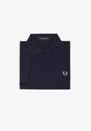 Polo shirt bleu marine en tissu texturé, présentant une patte de boutonnage à trois boutons et un logo de laurier brodé blanc sur la poitrine.