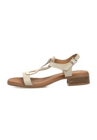 Sándalo beige con un diseño de tira en T, parte superior texturizada, correa ajustable en el tobillo y un tacón bajo en bloque. Plantilla suave con un acabado natural.