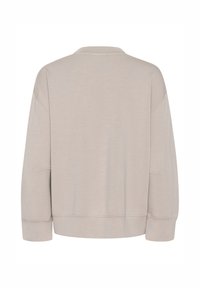 Ljusbeige sweatshirt med avslappnad passform, mjuk textur, vida ärmar, rund hals och synliga sömmar längs fållen.