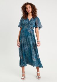 Robe midi fluide en teal avec des manches volantes, un décolleté en V et un motif détaillé complexe. Présente une taille définie et un tissu léger.