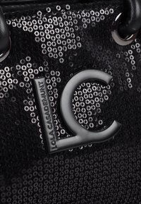 Sac à main noir en sequins avec un logo noir distinctif portant la mention "Lola Casademunt" et un design stylisé "LC".