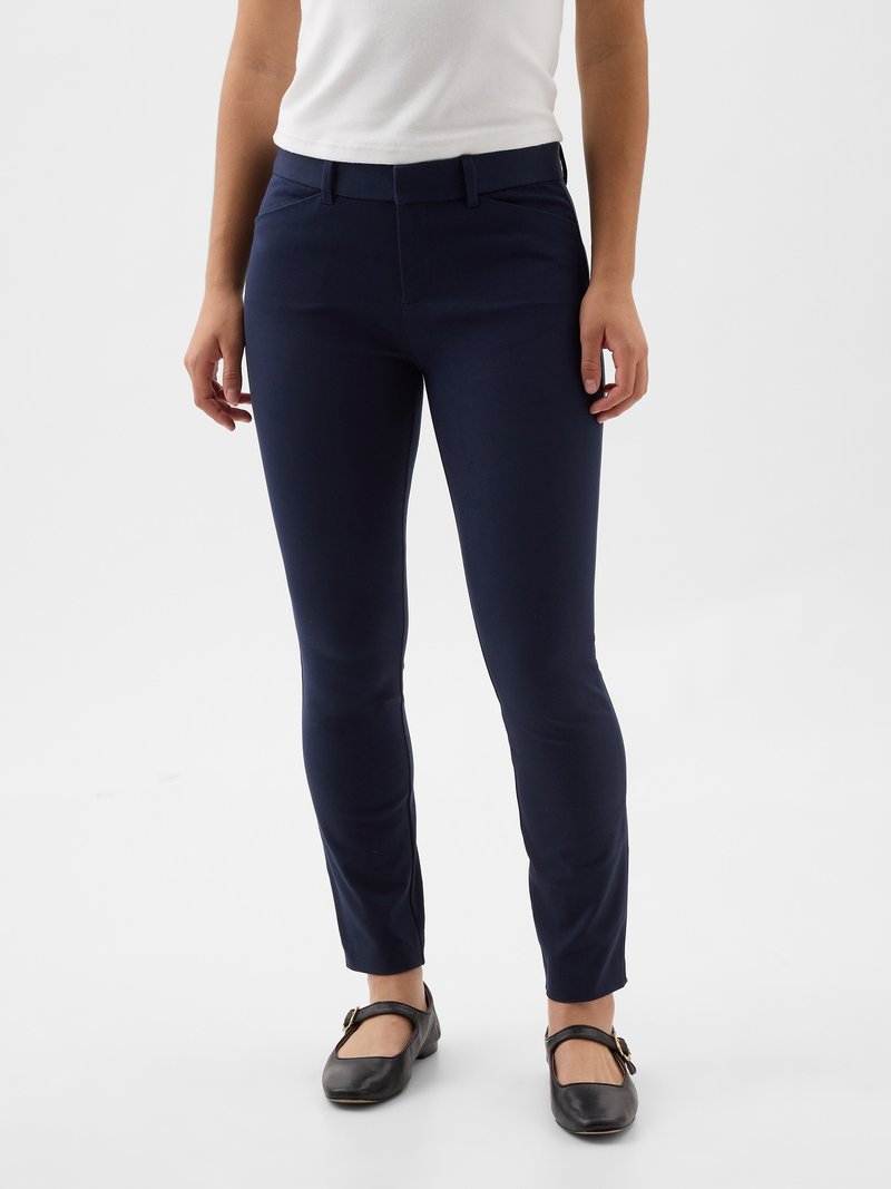 Navy slim-fit trousers made of a smooth fabric, featuring a flat front, belt loops, and a cropped length, paired with black flats.