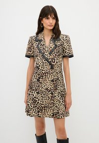 Abito con stampa leopardata, maniche corte, colletto nero e chiusura con bottoni. Il tessuto presenta una texture morbida con accenti a contrasto.