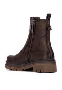 Bota de piel marrón hasta el tobillo con una cremallera lateral. Cuenta con un acabado texturizado, una suela marrón resistente y un tacón bajo.