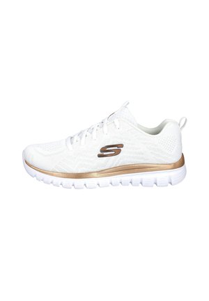 Zapatilla deportiva blanca con logo dorado y detalle dorado en la suela, con tejido de malla y cordones blancos, vista lateral aislada sobre fondo blanco.