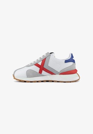 Zapatillas deportivas con material blanco perforado, detalles en ante gris, acentos en rojo y azul, suela de goma y cordones planos.