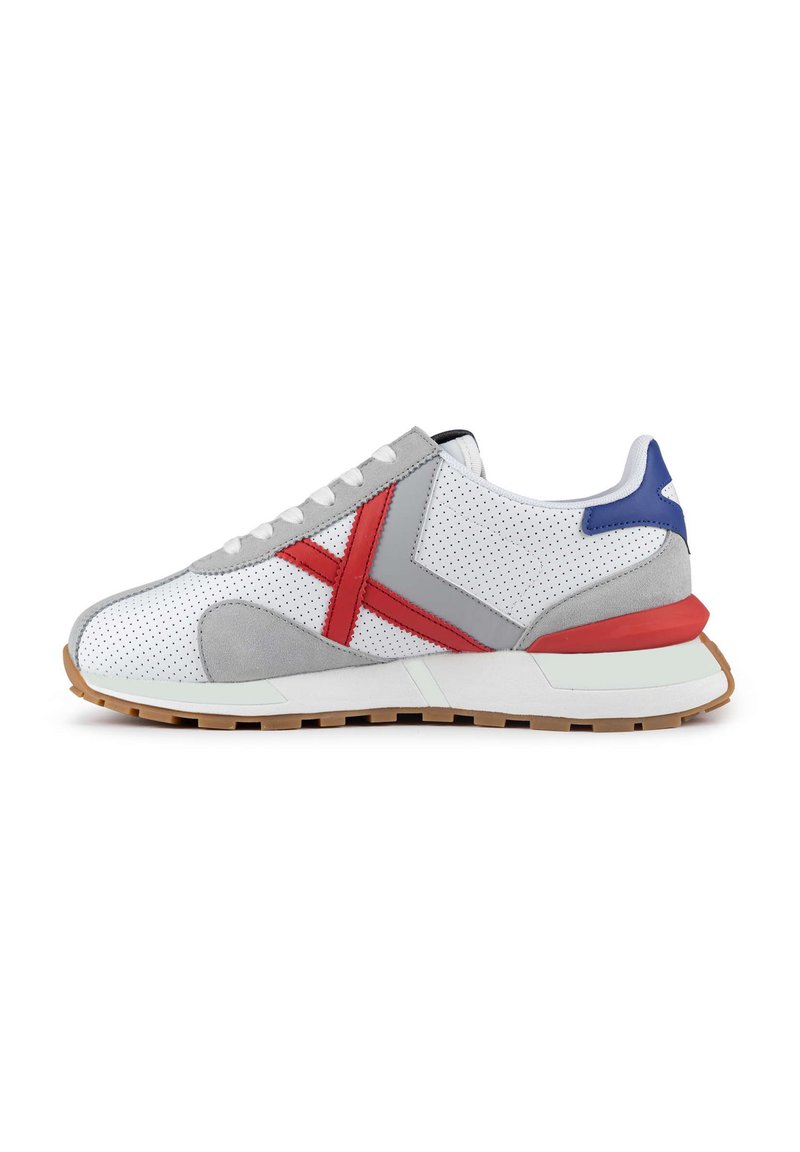 Zapatillas deportivas con material blanco perforado, detalles en ante gris, acentos en rojo y azul, suela de goma y cordones planos.