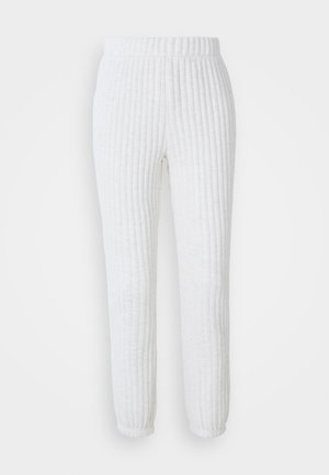 White ribbed jogger pants with an elastic waistband and tapered cuffs. Soft texture and a consistent pattern throughout the fabric.
