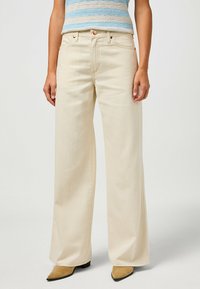 Breda beige jeans i denim med en slät yta, med framfickor, knappst�ängning och kontrasterande sömmar.
