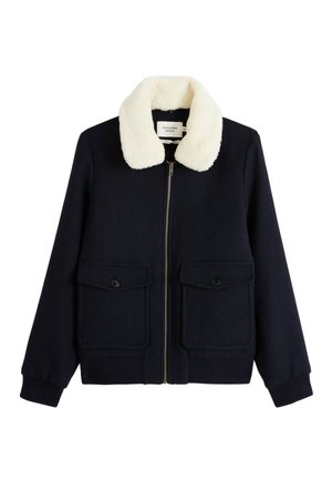 Veste en mélange de laine bleu marine avec un col en fausse fourrure beige, fermeture éclair à l'avant et deux poches poitrine à bouton. Tissu texturé avec des poignets côtelés.