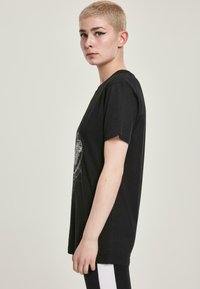 Sort bomulds T-shirt med korte �ærmer og rund hals, med et grafisk design på forsiden. Regular fit, glat tekstur.