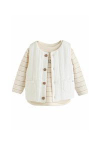 Chaleco blanco texturizado con botones marrones sobre una camisa de manga larga en tonos crema y beige a rayas que presenta un estampado gráfico.