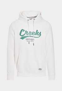 Sudadera blanca con un gráfico en color teal que dice "Creeks Original Desde 1974", bolsillo canguro frontal y capucha con cordones de metal.