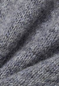 Tissu en laine dans des nuances de gris, présentant un motif de tricot texturé avec des fibres visibles, créant une apparence douce et chaude.