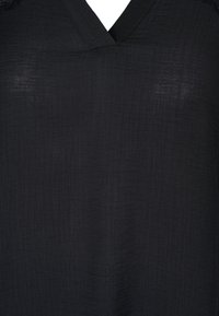 Blusa nera a scollo a V realizzata in tessuto leggero e testurizzato. Presenta un motivo leggermente stropicciato e una vestibilità rilassata.
