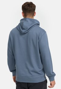 Hooded sweatshirt in soft, medium blue fabric. Features ribbed cuffs, a relaxed fit, and a smooth texture. Design emphasizes simplicity.
