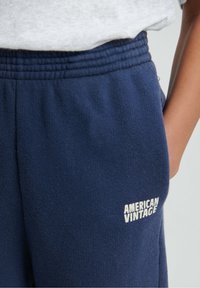 Tumši zili sporta bikses no mīksta auduma, ar elastīgu vidukļa joslu un sānu kabatām. "AMERICAN VINTAGE" balts logo pie vidukļa joslas.