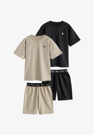 Zwei Sets aus legeren T-Shirts mit kurzen Ärmeln und Shorts, eines in Beige mit "WC"-Logo, eines in Schwarz mit Totenkopf-Logo, beidseitig mit elastischen Taillenbändern, die mit "Next" beschriftet sind.
