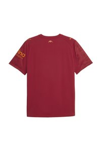 Bordo sportska majica s okruglim izrezom, kratkim rukavima i glatkom teksturom. Ima žute akcentne boje i logotipe na ramenima.