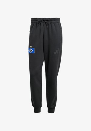 Czarne spodnie dresowe adidas z elastycznymi ściągaczami, paskiem ze sznurkiem, kieszeniami po bokach oraz niebiesko-białym logo drużyny sportowej ze złotą gwiazdą na lewym udzie.