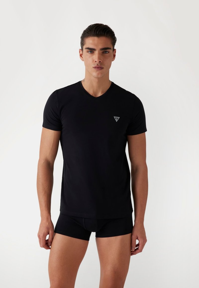 T-shirt nera a maniche corte con scollo a V, realizzata in tessuto morbido, con un piccolo logo a triangolo sul lato sinistro del petto, progettata in uno stile aderente.