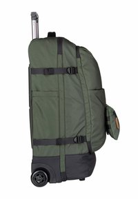 Valise souple verte avec accents noirs, deux roues, une poignée rétractable, des poches latérales et des sangles pour sécuriser les objets. Tissu texturé.