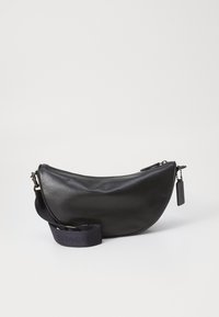 Borsa nera in pelle a forma di mezzaluna con chiusura a zip, dotata di una tracolla in tessuto scuro con dettagli del logo e un piccolo cartellino. Texture liscia.