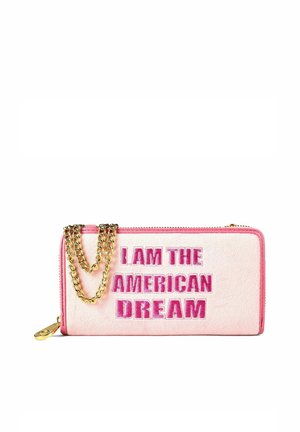 Pinkes rechteckiges Portemonnaie mit goldener Kette und dem in fetten pinken Buchstaben bestickten Schriftzug „I AM THE AMERICAN DREAM“ auf der Vorderseite.