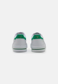 Hvide sneakers med grønne accenter og et gyldent logo, med en glat overflade og polstret ankelkrave for komfort. Gummisål med grøn stribe.
