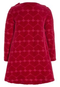 Punainen samettimekko pitkillä hihoilla, jossa on kaikille näkyvä sydänkuvio, pyöreä kaula-aukko ja lievä flare helmaa kohti.