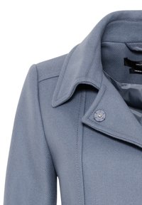 Cappotto grigio chiaro con collo strutturato, tessuto texturizzato e dettaglio di un solo bottone sulla revers.