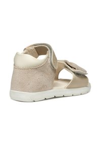 Sandalini per bambini beige con tomaia in suede, dettagli in pelle, lati aperti, cinturino in velcro e suola in gomma bianca testurizzata.