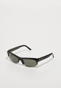 Lunettes de soleil noires rectangulaires avec des verres verts. Monture en plastique lisse et brillante avec des accents dorés. Les branches présentent un détail de logo et un design minimaliste.