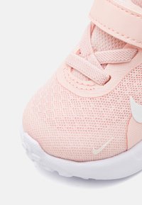 Baskets de sport en mesh rose avec une surface texturée, accents blancs, sangle ajustable et fermeture à lacets. Conception légère avec un bout arrondi.