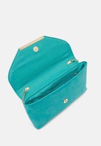 Türkisfarbene Stoff-Clutch-Tasche geöffnet, um die Innenfächer zu zeigen, mit einem goldenen Verschluss und einem Reißverschlussfach, glatter Textur und kantigem Design.