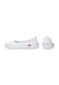 Witte canvas instapschoenen met een contrasterende bruine accent bij de hiel en een gestructureerde rubberen zool met ribbels.