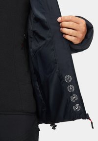 Czarna wodoodporna kurtka z gładką podszewką, prezentująca etykiety dotyczące odporności na wodę, oddychalności i cech ekologicznych.