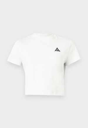 Hvid crop-top T-shirt med korte ærmer og et lille sort trekantet logo på venstre bryst med teksten "acg".