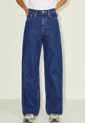 Bredde jeans i blå denim med høj talje, klassisk fem-lomme design og subtile sømdetaljer. Stylet med grå sneakers.