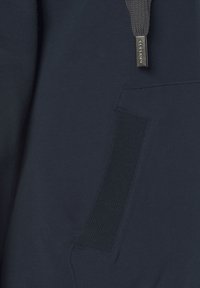 Felpa blu navy in tessuto liscio, con un'apertura a tasca ribattuta e un cordino piatto al collo con hardware metallico.