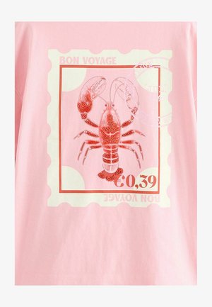 T-shirt rosa con una grafica di un'aragosta rossa, incorniciata da un design di francobollo bianco con il testo "BON VOYAGE" e "€0,39".