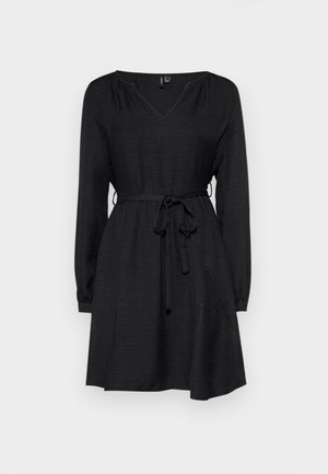 Mustas kleit pika varrukaga, V-dekoltee, kokku tõmmatud talje sidumisvõimalusega vööd, ning voolav seelik. Valmistatud tekstureeritud kangast.