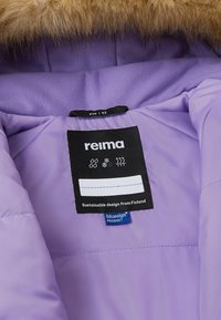 Interior de chaqueta morada con una etiqueta negra que muestra la marca, la talla (92) y símbolos de cuidado. Un suave ribete de piel añade calidez.