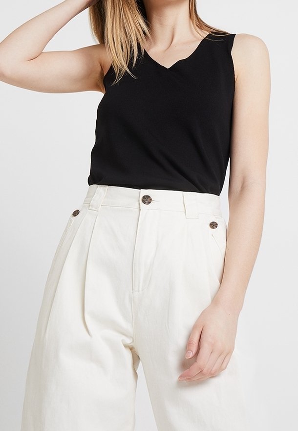 Black sleeveless top with a v-neckline and relaxed fit paired with high-waisted white wide-leg trousers featuring two front buttons.