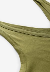 Débardeur en coton vert olive avec des bretelles larges, un décolleté arrondi et des coutures plates pour une finition lisse. Texture douce et design décontracté.